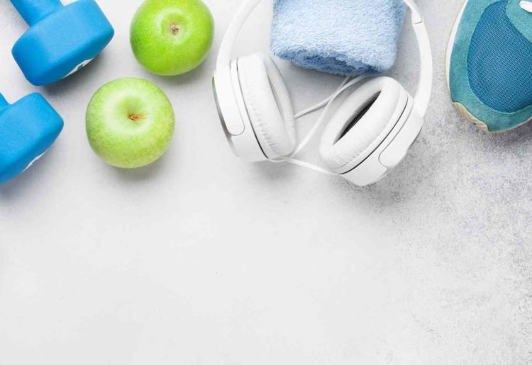 Vandflaske, håndvægte, æbler, høretelefoner og træningssko